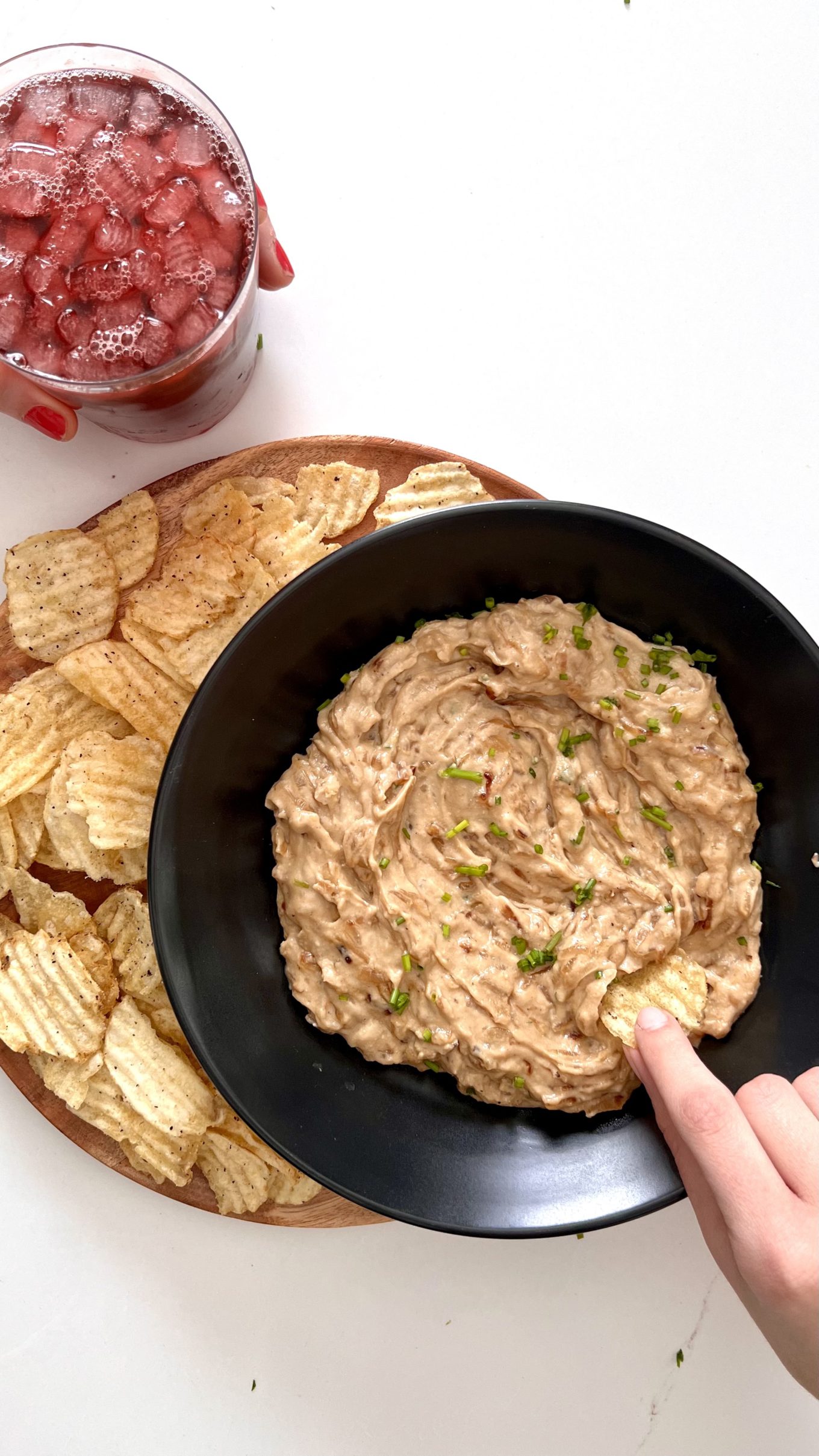 A person is dipping a plate of vegan salsa into a plate of salsa.
