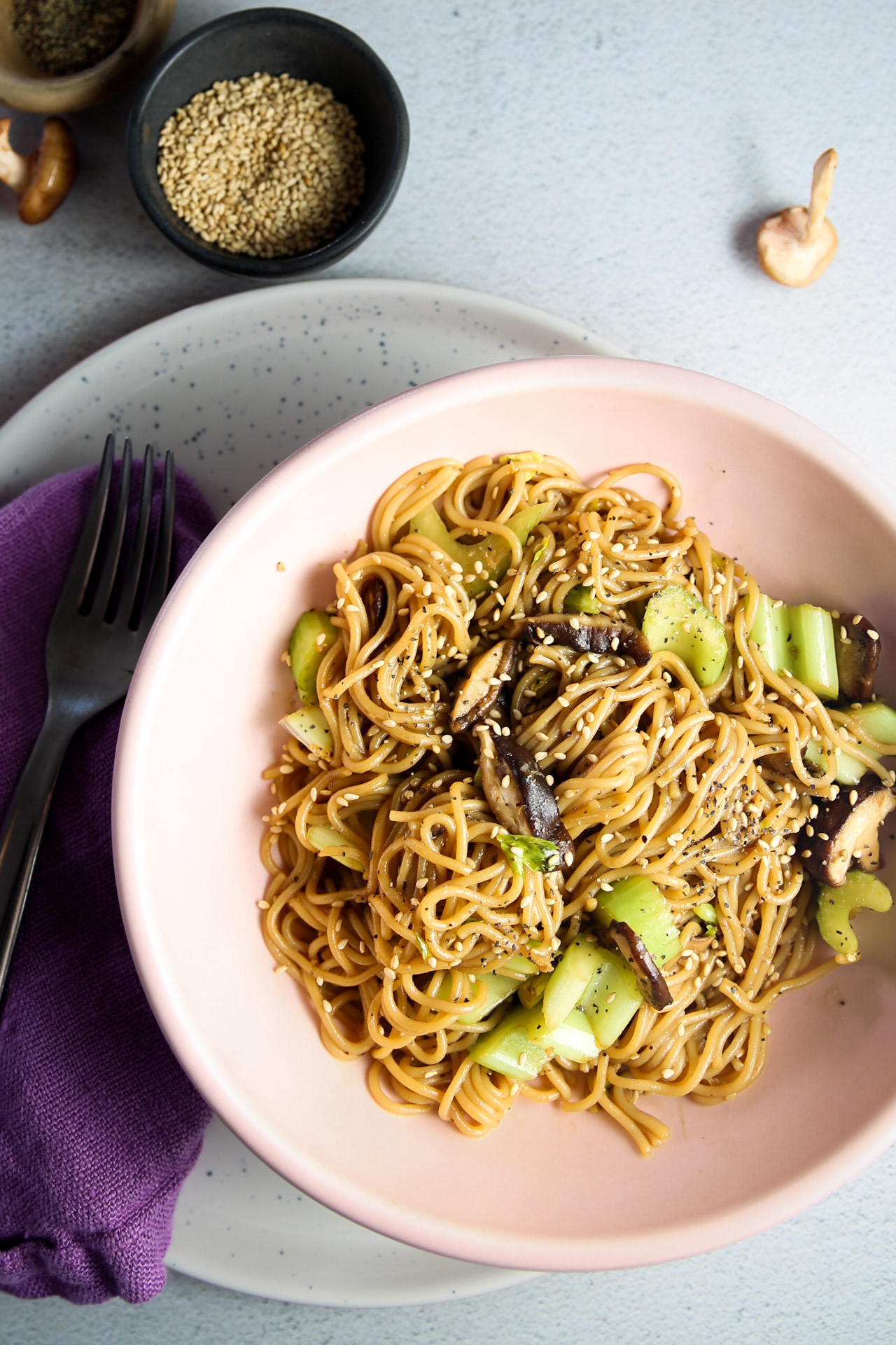 A bowl of noodles with mushrooms and black pepper sprinkled with sesame seeds.