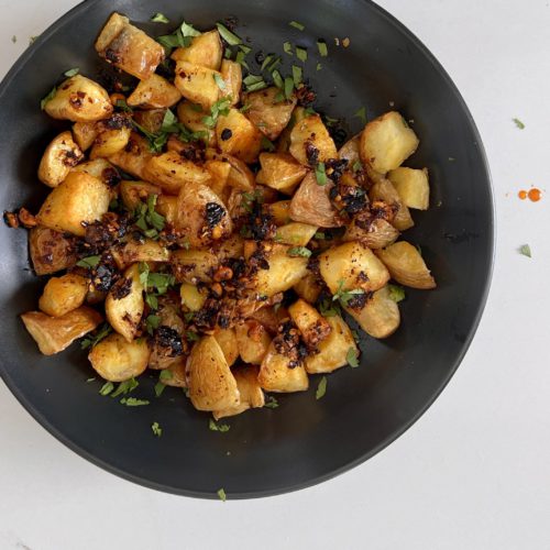 Papas machas on a black plate with herbs.