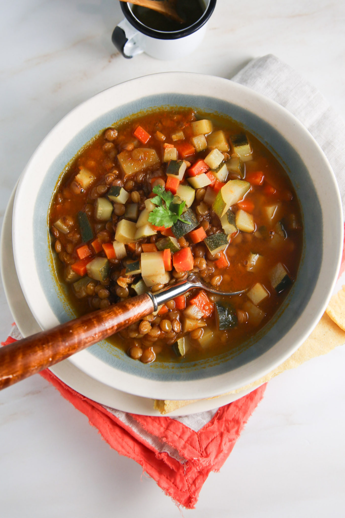A bowl of lentil soup with vegetables and a spoon.