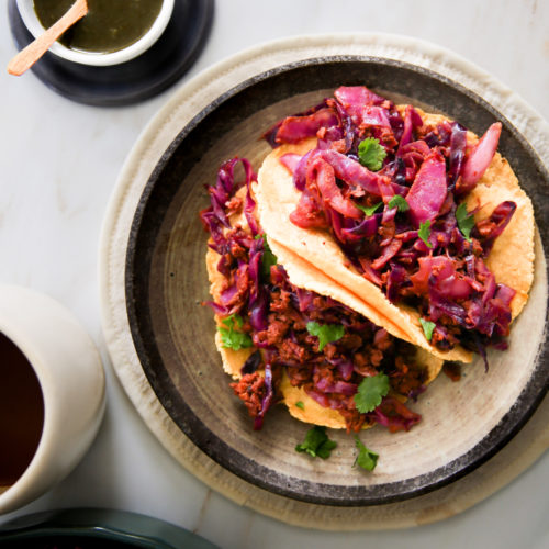 Red cabbage tacos on a plate with a cup of coffee.