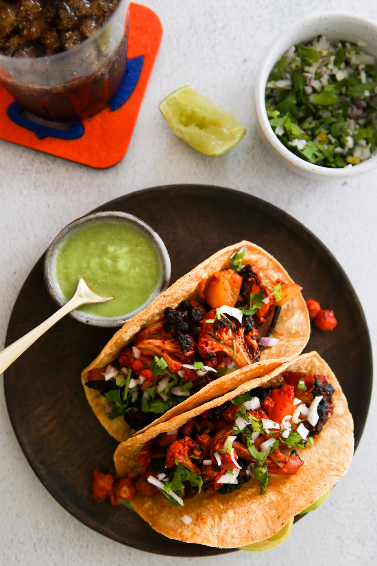 Two tacos on a plate next to a plate of guacamole.