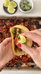 A person holding a taco with cauliflower on a baking sheet.