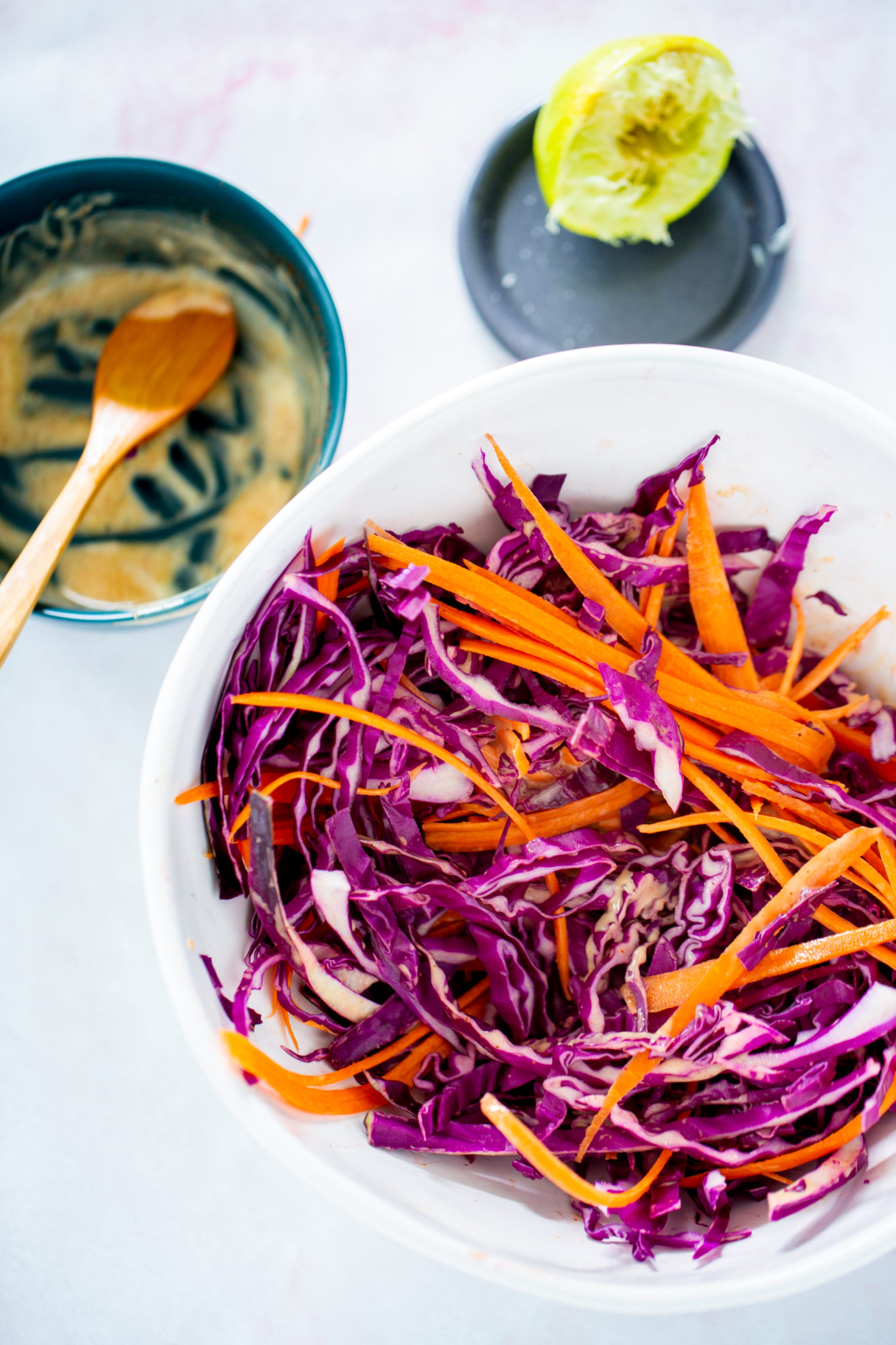 A bowl of cabbage and carrots in a white bowl with a spoon.