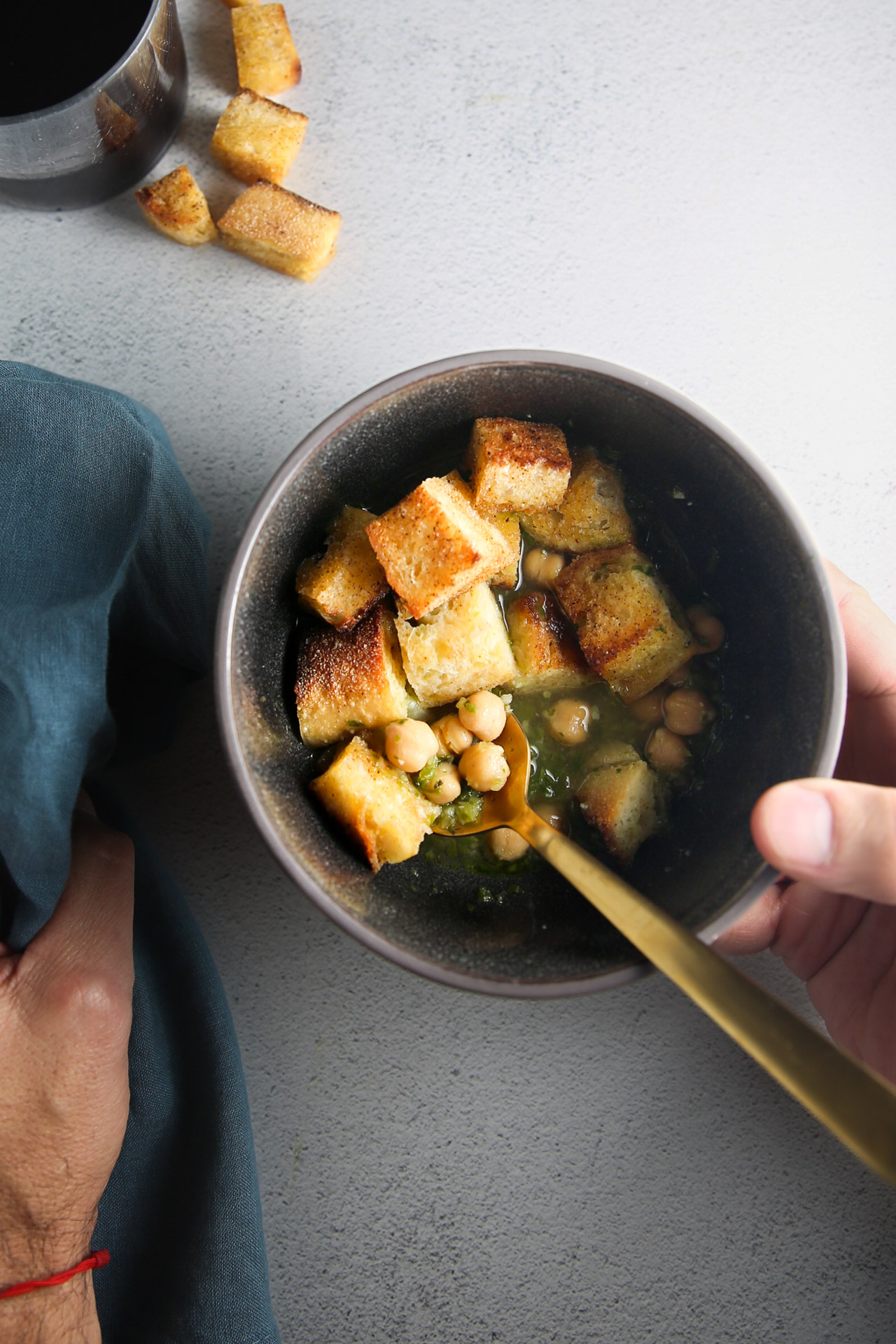 Croutons in a bowl with a person holding a spoon for Portuguese Soup.