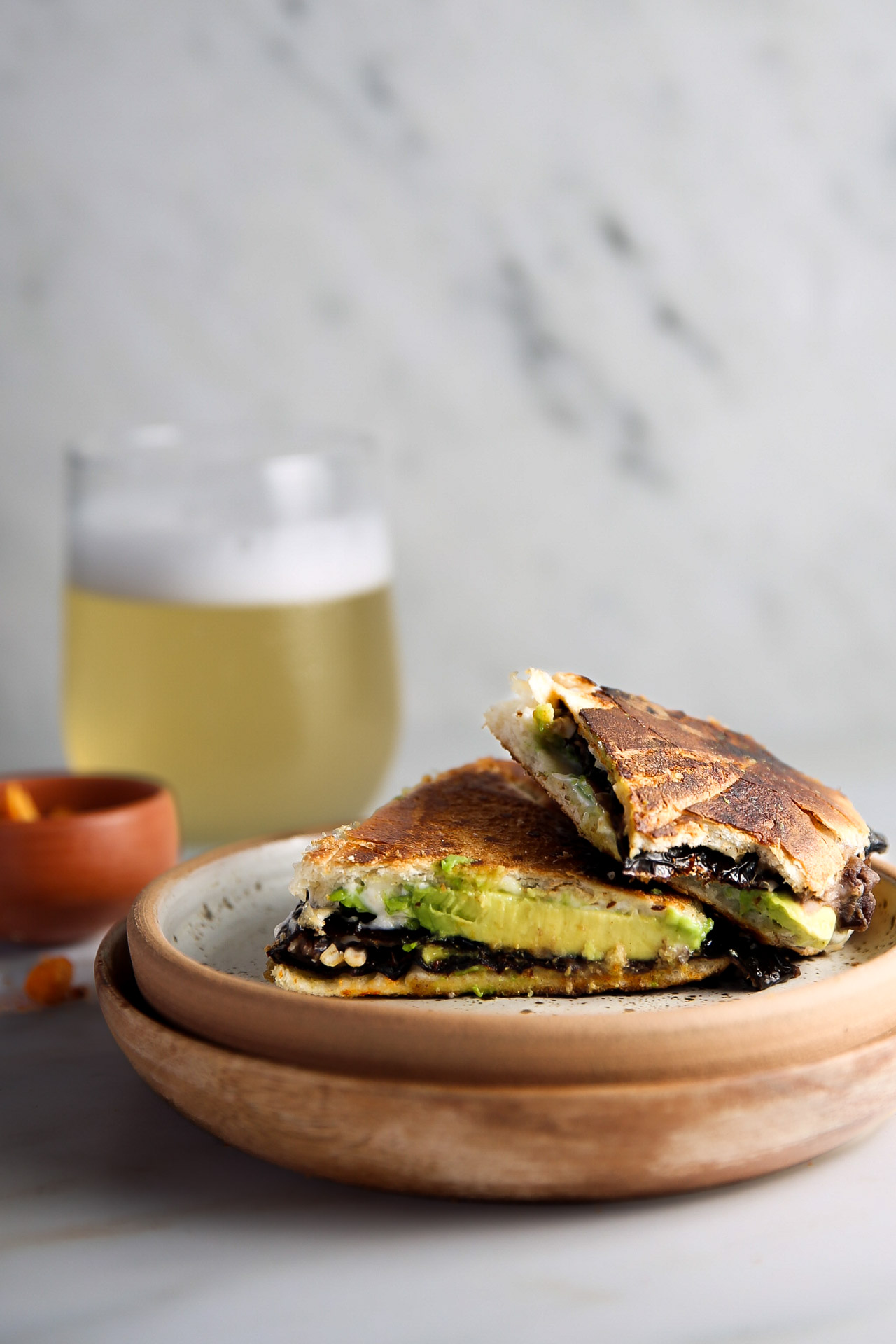 An ancho chile tortas quesadilla on a plate next to a glass of beer.