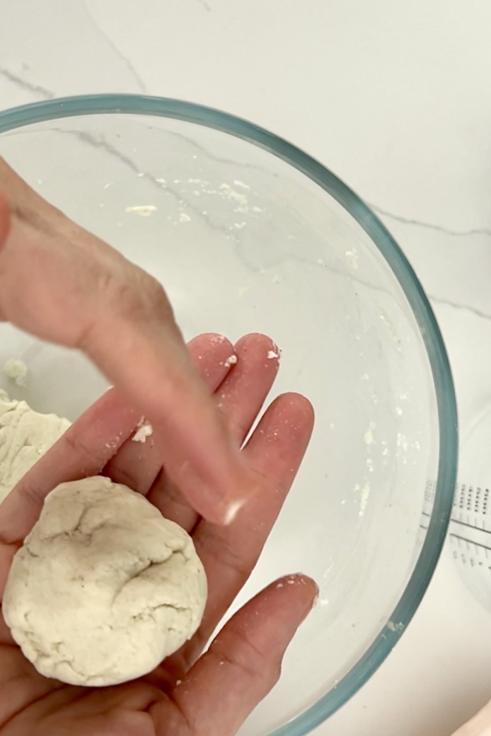 making masa harina dough balls over a glass bowl