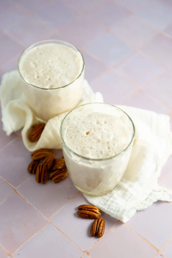 Two clear glasses filled with a pecan milk,